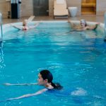 Adults relaxing and swimming in a serene indoor pool setting, perfect for leisure and recreation.