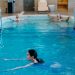 Adults relaxing and swimming in a serene indoor pool setting, perfect for leisure and recreation.